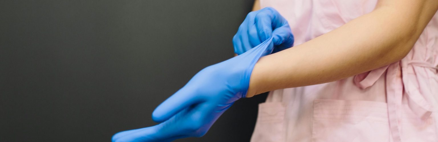Close-up of a healthcare worker putting on blue medical gloves for protection.